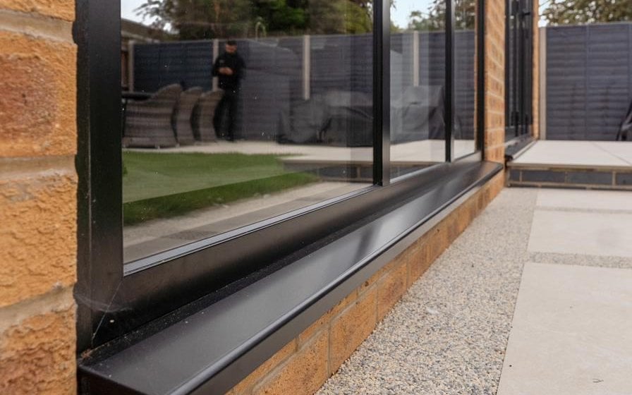 Slim-framed aluminium picture window with dark powder-coat finish on a Peterborough extension