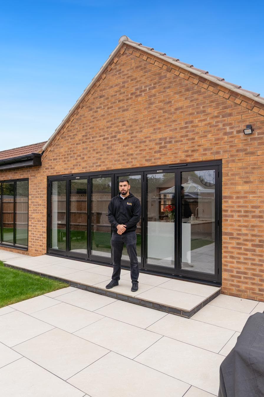 Tariq from Custom Choice in front of newly-installed Origin anthracite aluminium bifold doors on a Peterborough rear extension
