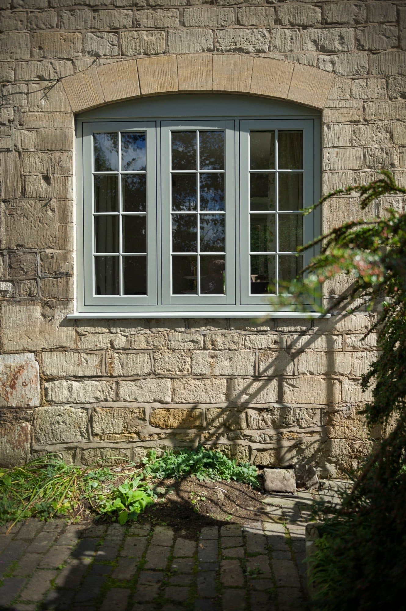 Arched window with Georgian glazing bars in a stone cottage wall