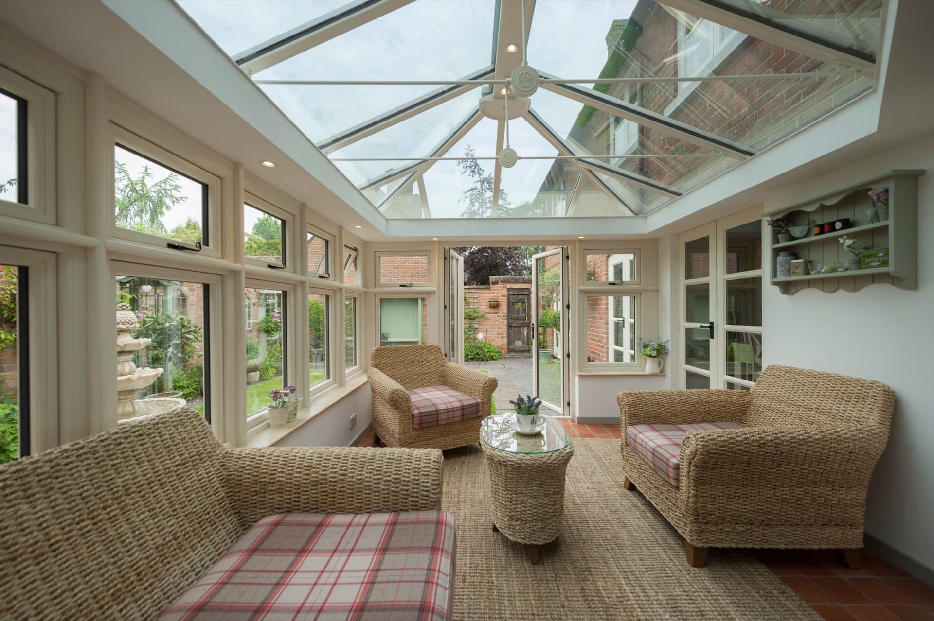 Conservatory interior with wicker seating beneath a glazed roof lantern