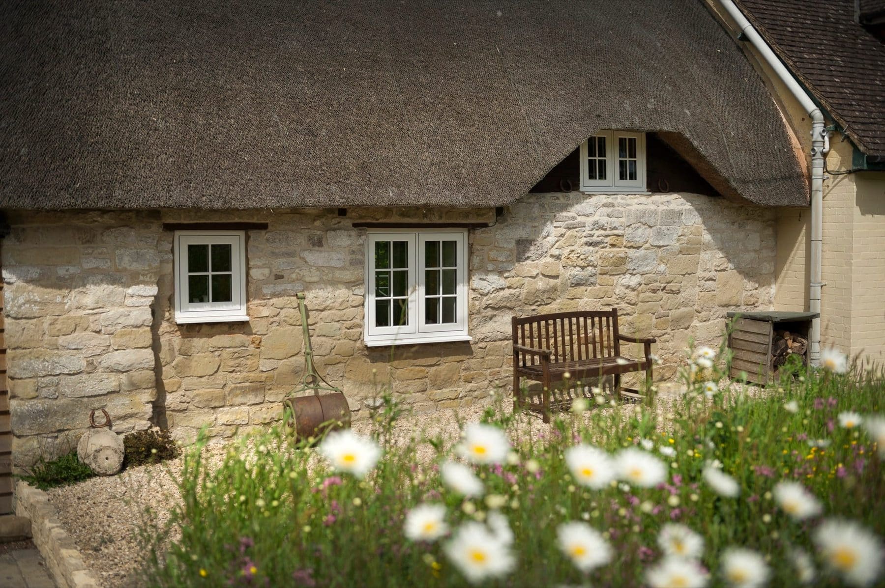 White flush-sash uPVC casement windows on a thatched stone cottage