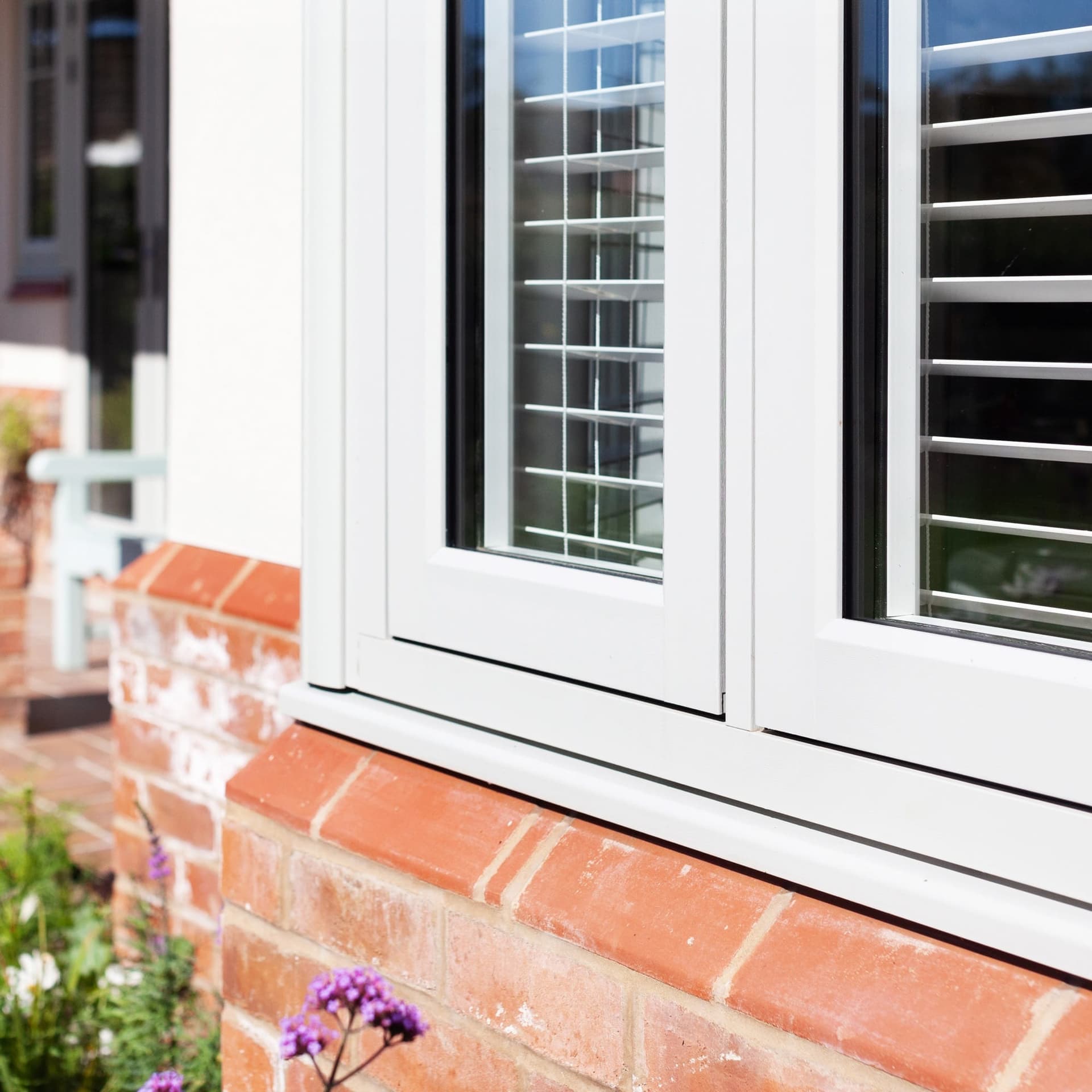 Classic white flush-sash uPVC casement window on a red brick home — close-up detail