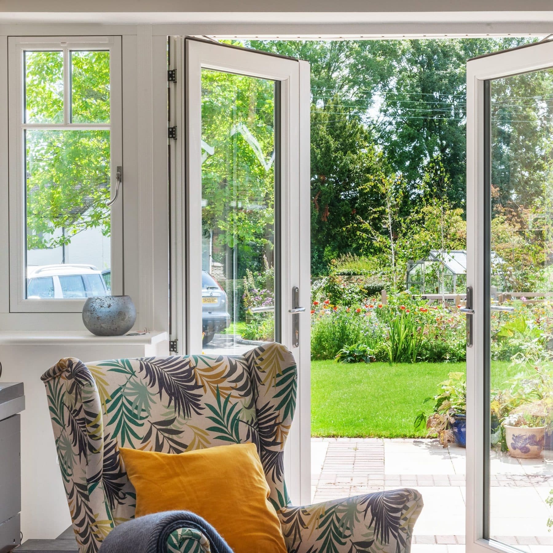 White Origin aluminium French doors opening from a sitting room onto a sunlit garden