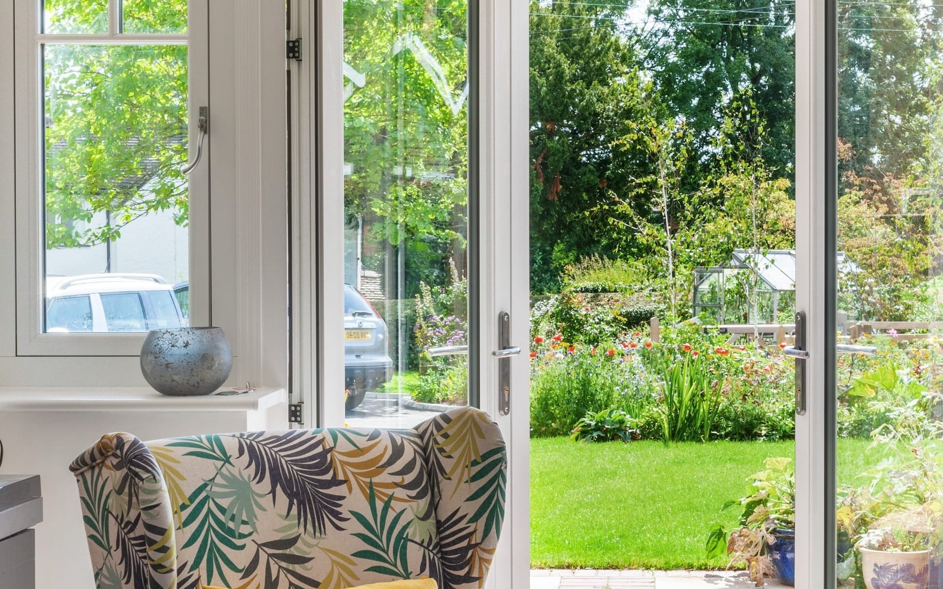 White aluminium French doors opening from a sitting room onto a sunlit garden — Custom Choice install